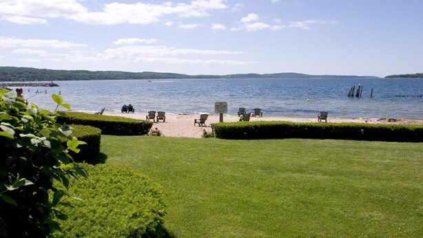 A well-maintained grassy area with several chairs and a sign indicating no swimming. - Water Street Inn (Boyne City)