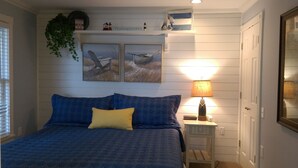 A bedroom with a bed, a nightstand, a lamp, and two wall-mounted paintings. - Water Street Inn (Boyne City)