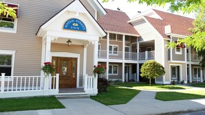 A two-story hotel with a prominent entrance, a balcony on the second floor, and a well-maintained lawn. - Water Street Inn (Boyne City)