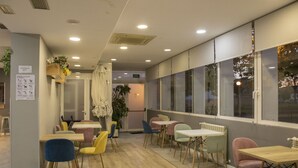 Un restaurant avec plusieurs tables et chaises, une plante et une fenêtre donnant sur un beau paysage.