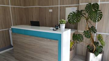 A reception desk with a wooden backdrop, a potted plant, and a sign on the wall.
