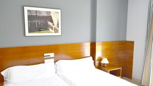 Une chambre d’hôtel avec un grand lit, une tête de lit en bois, une table de chevet avec une lampe et un tableau encadré au mur.