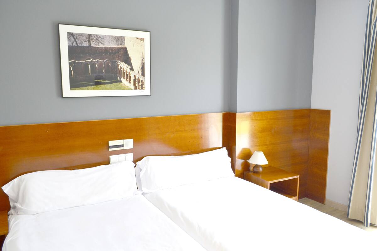 Ein Hotelzimmer mit einem großen Bett, einem hölzernen Kopfteil, einem Nachttisch mit Lampe und einem gerahmten Bild an der Wand.