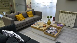 Un salon moderne avec un canapé gris, une table basse sur laquelle sont posés des magazines et un vase avec des plantes.