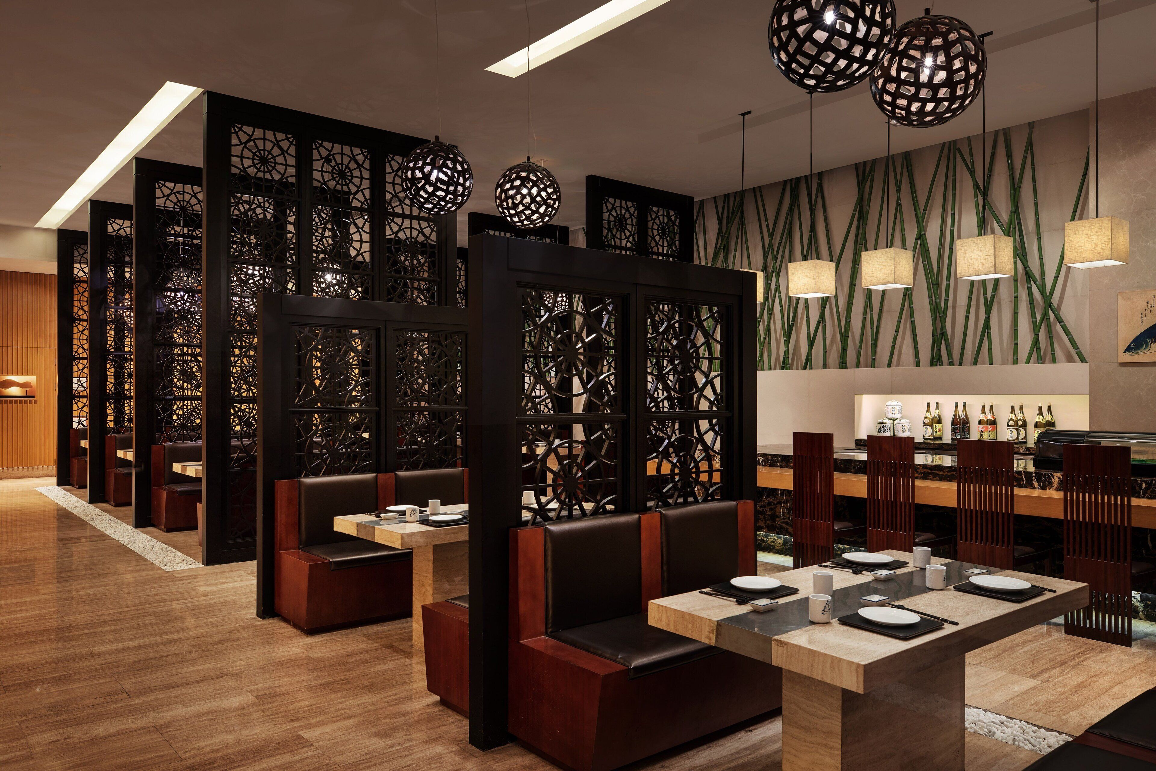 A restaurant with wooden flooring, black and brown booths, and tables set for dining.