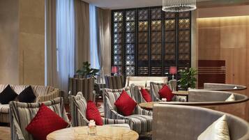 Ein stilvoller Lounge-Bereich mit gestreiften Sesseln, runden Tischen und roten Kissen.