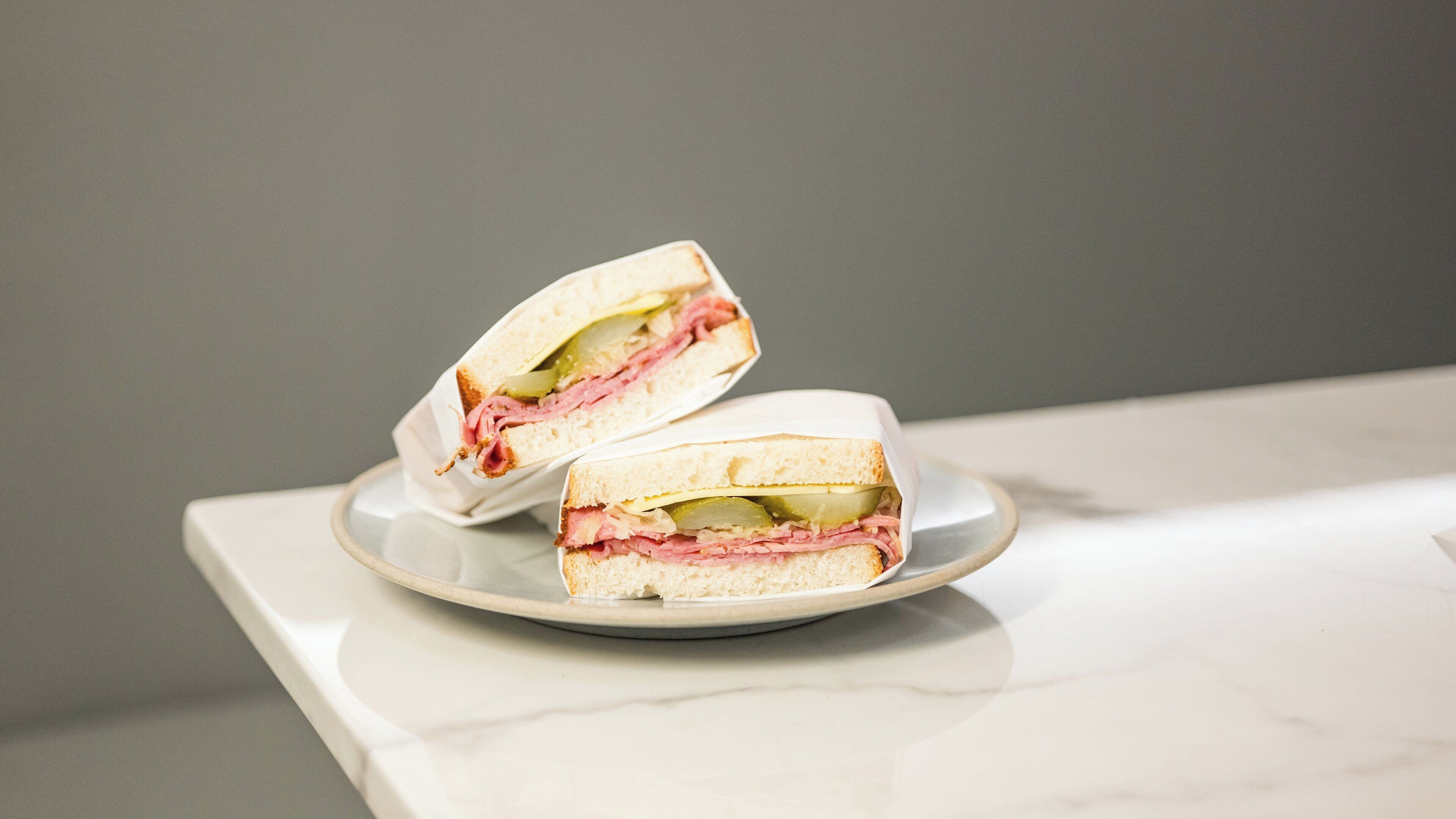 Un sándwich cortado por la mitad sobre un plato blanco.