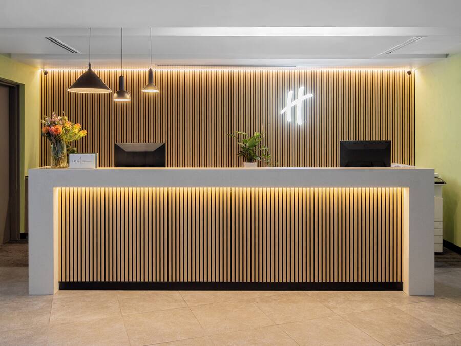 Una recepción de diseño moderno, con un panel de madera listonada e iluminación colgante.