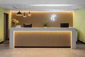 Una reception dal design moderno, caratterizzata da un pannello a listelli in legno e illuminazione a sospensione.