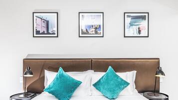A hotel room with a bed, two nightstands, and three framed pictures on the wall.