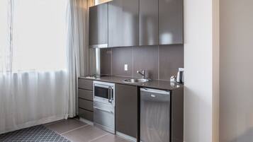 Una kitchenette compacta con horno integrado, un lavamanos y un refrigerador pequeño.