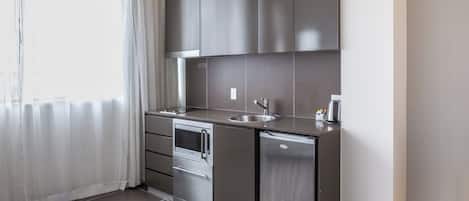 A compact kitchenette with a built-in oven, a sink, and a compact refrigerator.