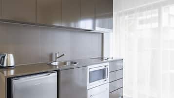 Una cocina moderna con electrodomésticos de acero inoxidable, un lavamanos y una ventana con cortinas translúcidas.