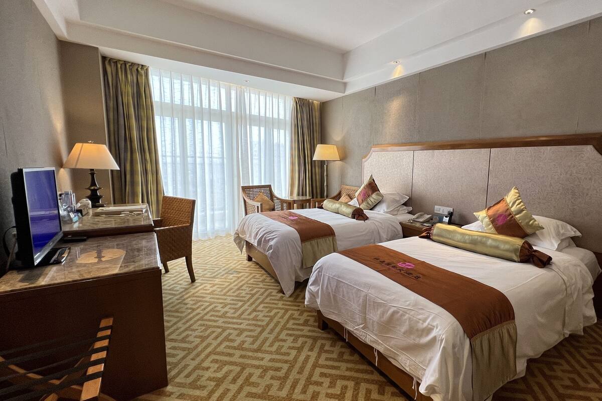 A hotel room with two beds, a desk with a computer, and a chair.