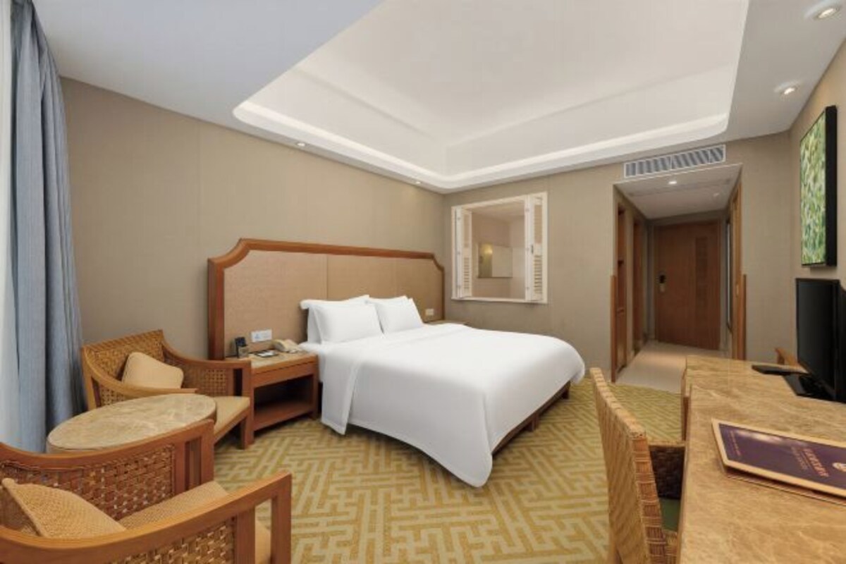 Una habitación de hotel con cama, mesita de noche, silla y televisor.