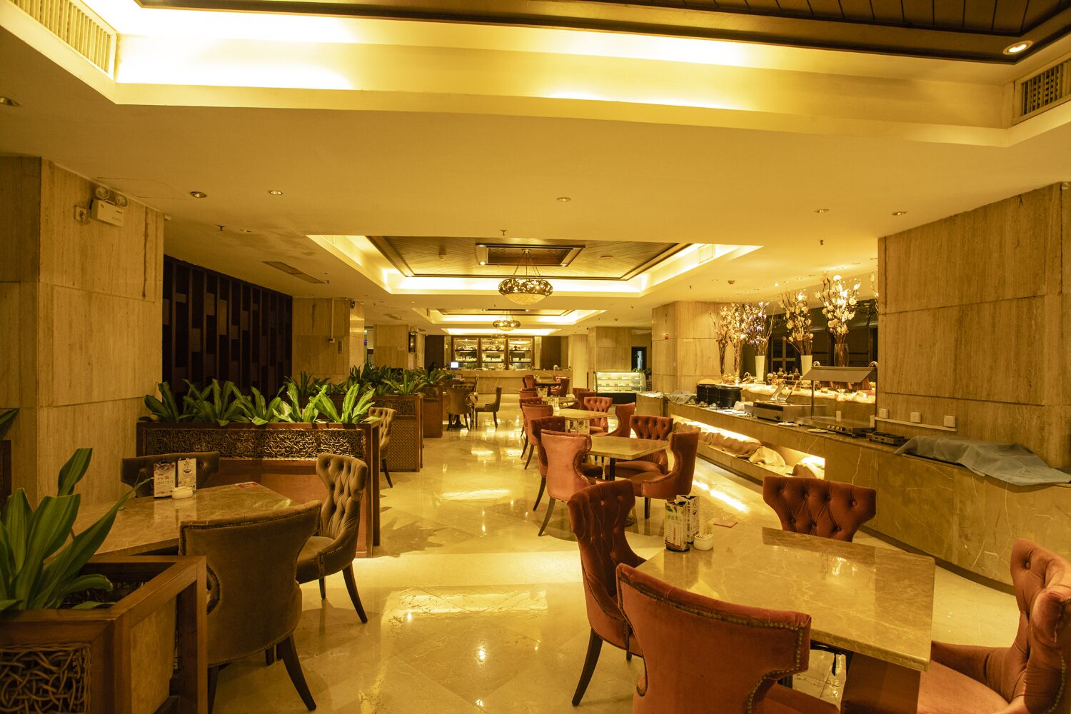 Eine großzügige Hotelhalle mit einer zentralen Sitzgelegenheit, einer Rezeption und einer Bar.