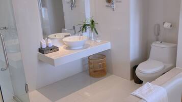 A modern bathroom with a glass shower enclosure, a white sink with a vessel basin, a freestanding bathtub, and a large mirror with wall-mounted lights.