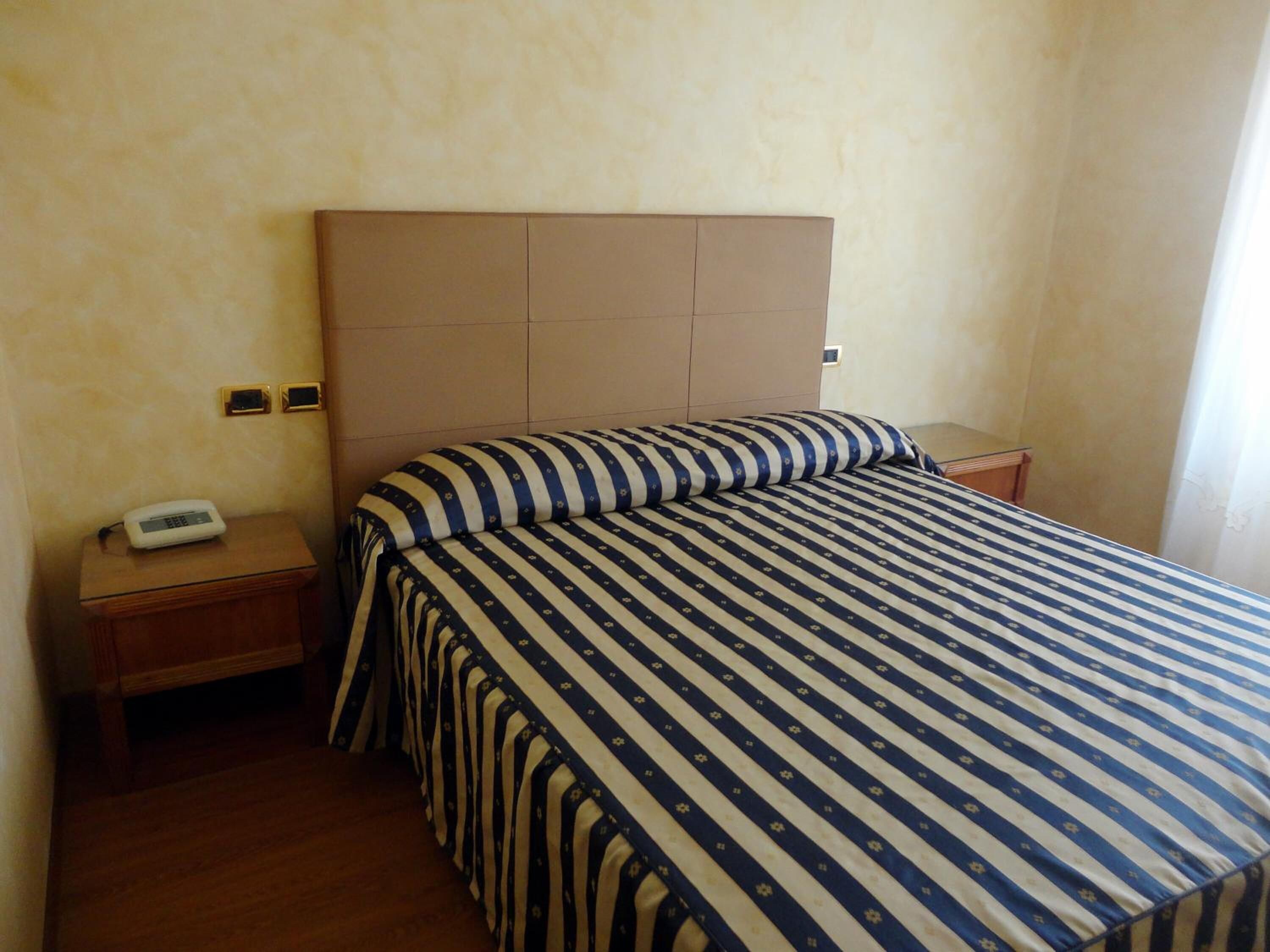 Una habitación de hotel con una cama, una mesita de noche y una mesilla.