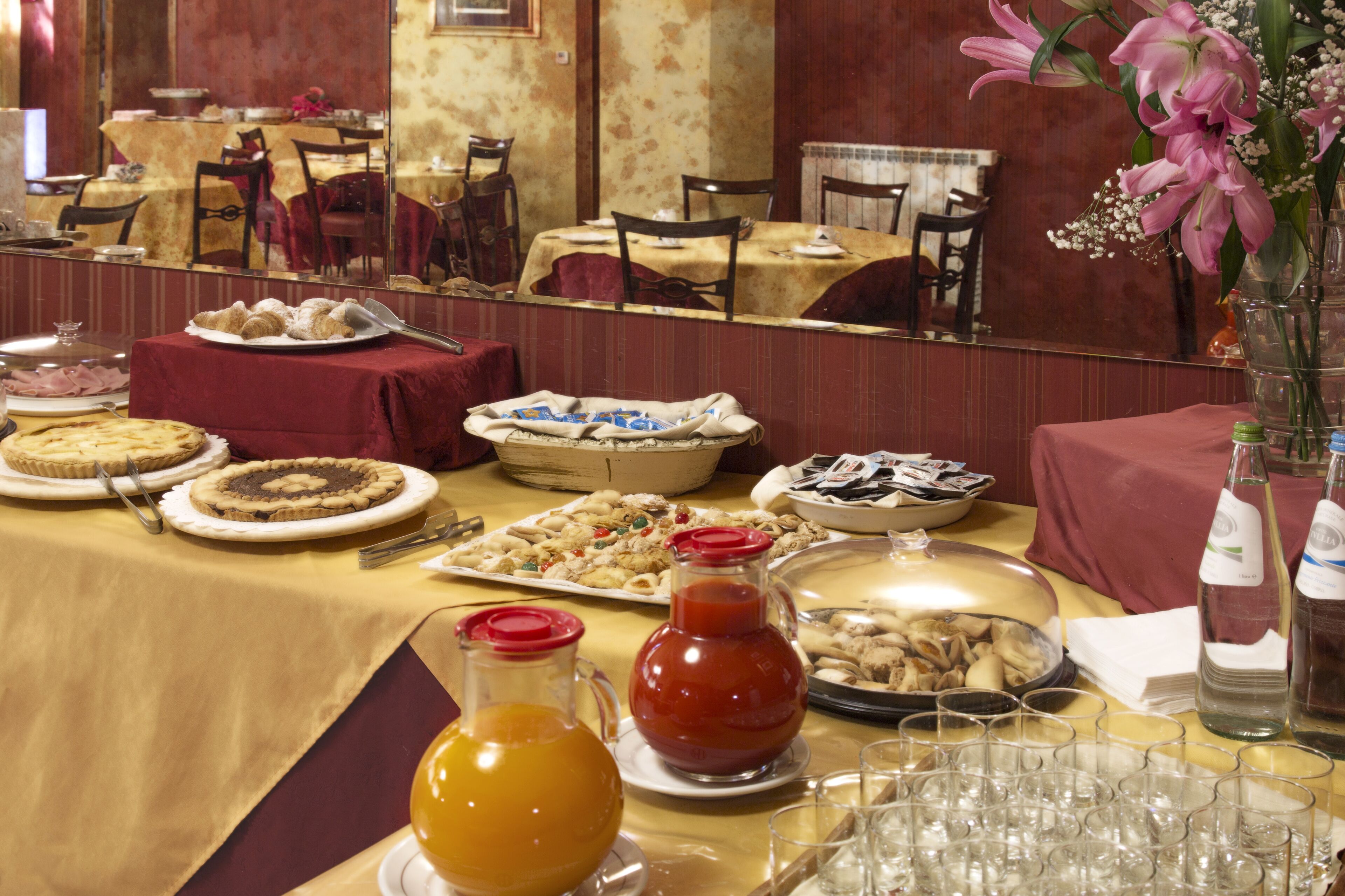Una mesa de buffet con diversos platos, una jarra de jugo y una botella de kétchup.