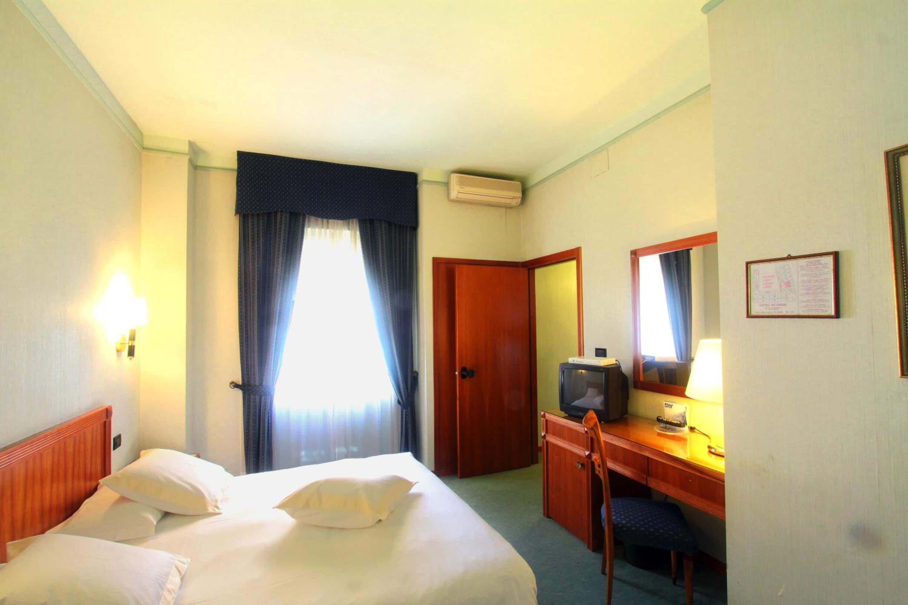 Une chambre d’hôtel équipée d’un lit, d’un bureau, d’une télévision et d’un appareil de climatisation.