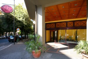 A hotel entrance with a large sign, a covered entrance, and potted plants. - Hotel de Paris (Terni)