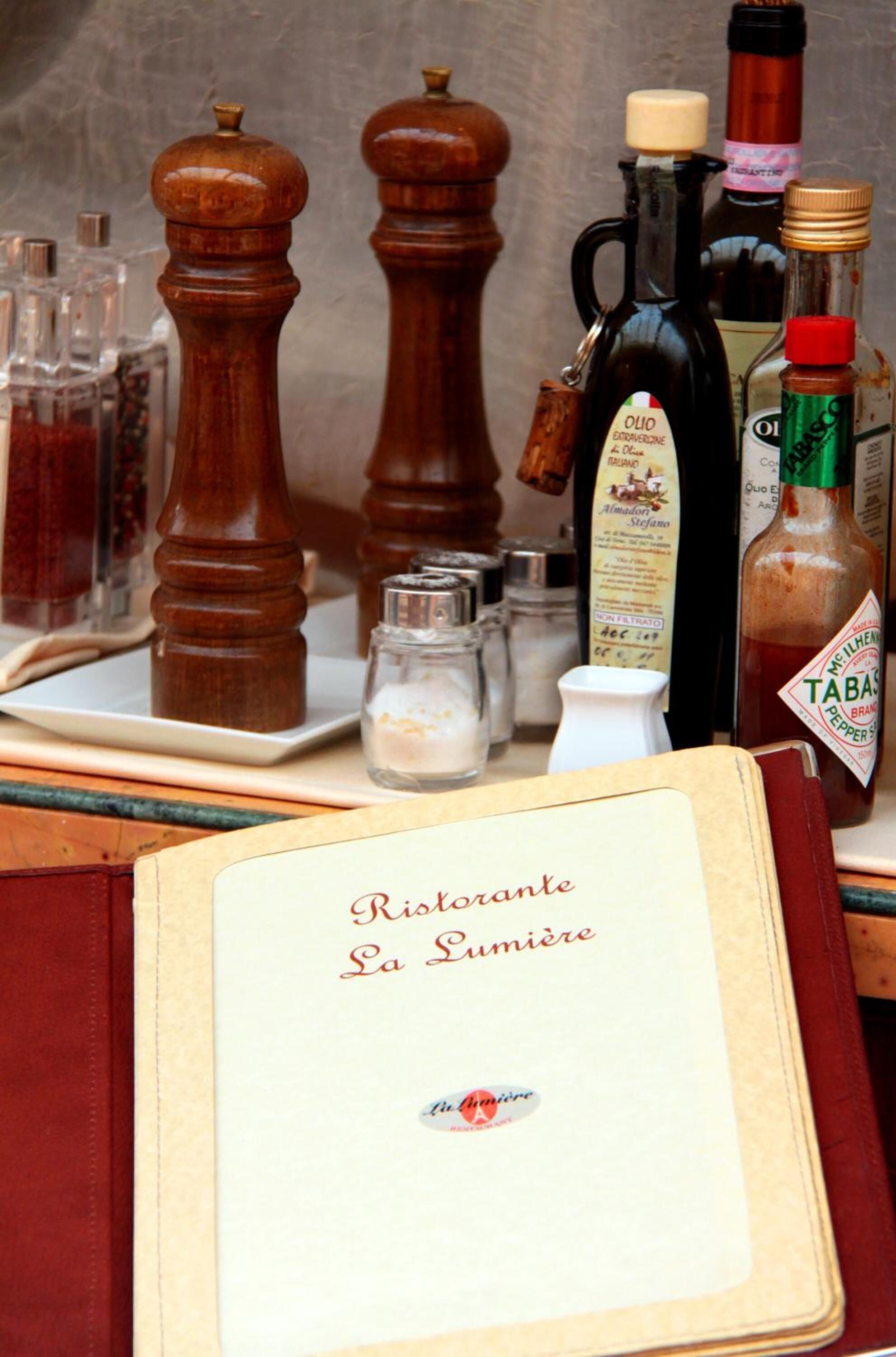 Un menù dal titolo "Ristorante La Sumiere" con diversi condimenti e bottiglie su un tavolo.