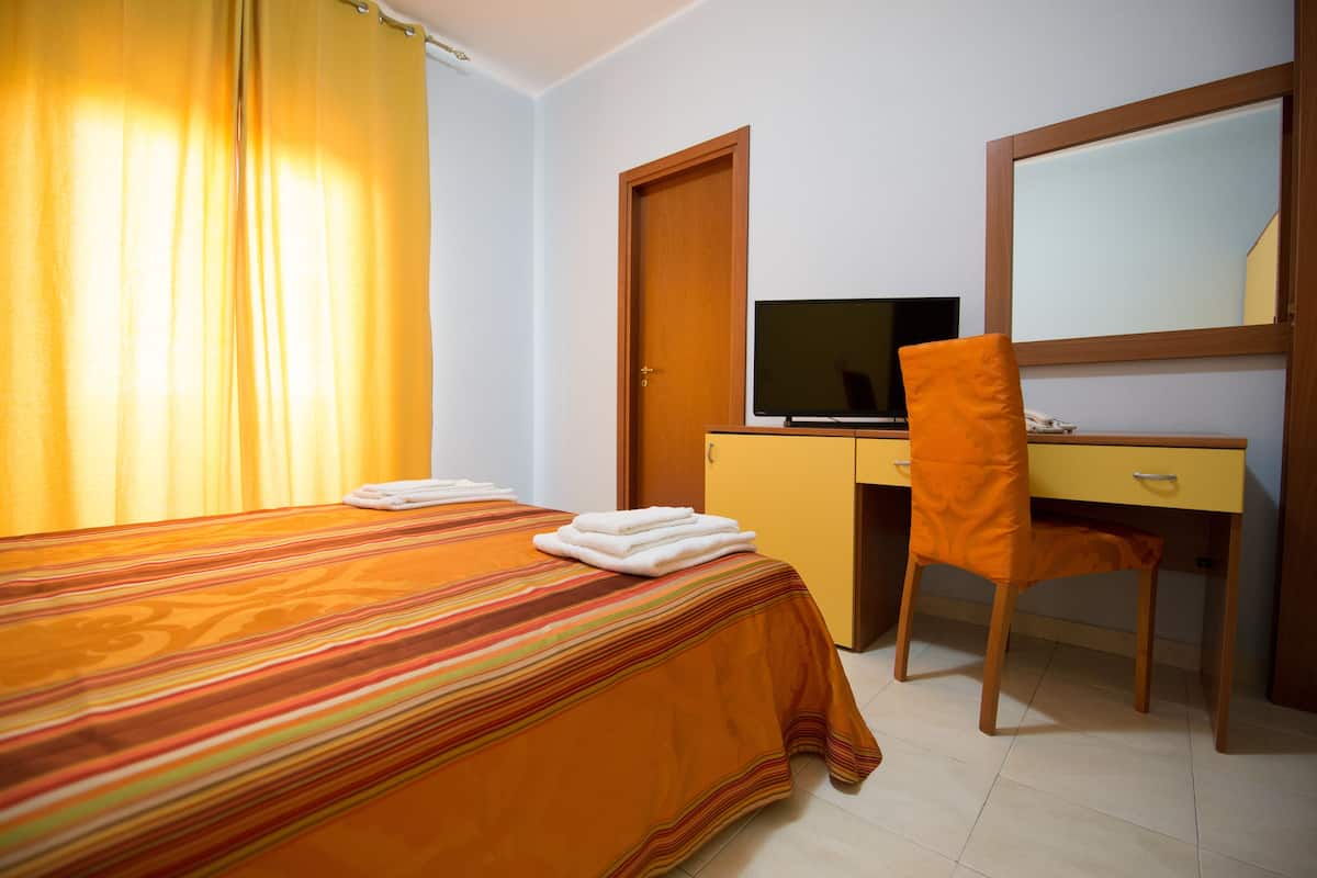 Una habitación de hotel con una cama, un escritorio con una computadora y una silla.