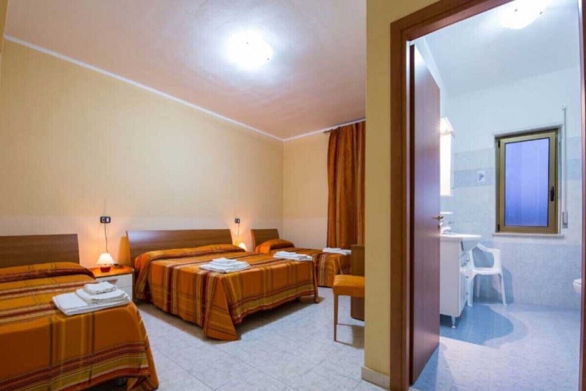 A hotel room with two beds, a small bathroom, and a view of the outside.