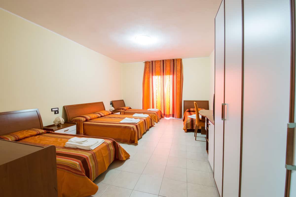Una habitación de hotel con cuatro camas, un escritorio y un armario.