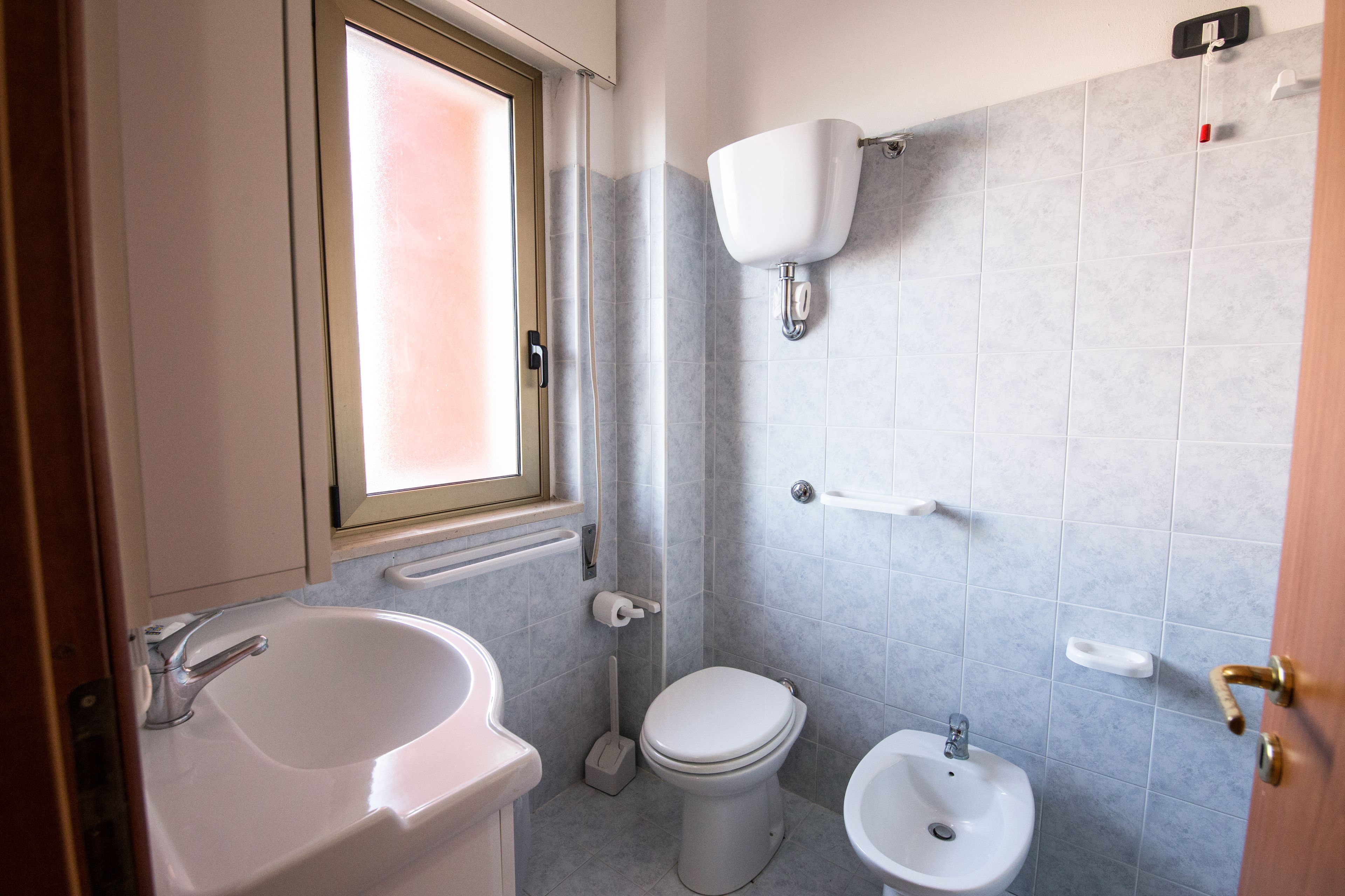Un bagno con lavandino, WC, bidet e una finestra.
