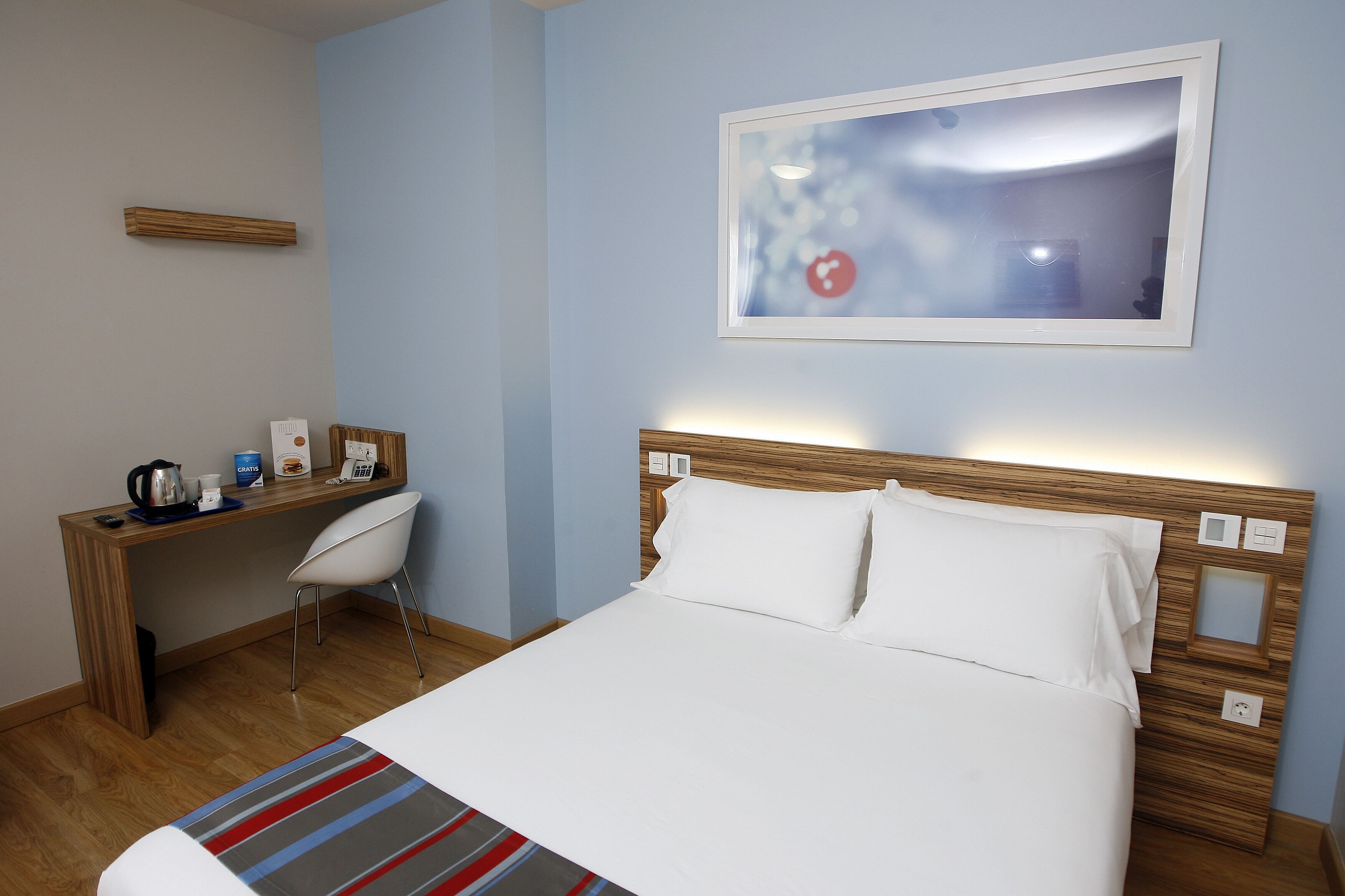 Ett hotellrum med en säng, ett skrivbord och en stol.