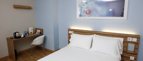 Ett hotellrum med en säng, ett skrivbord och en stol.