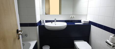 A small bathroom with a white sink, a toilet, a bathtub, and a mirror.