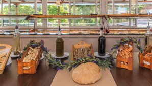 Una mesa con diferentes alimentos y botellas, frente a una ventana con vista a la vegetación.