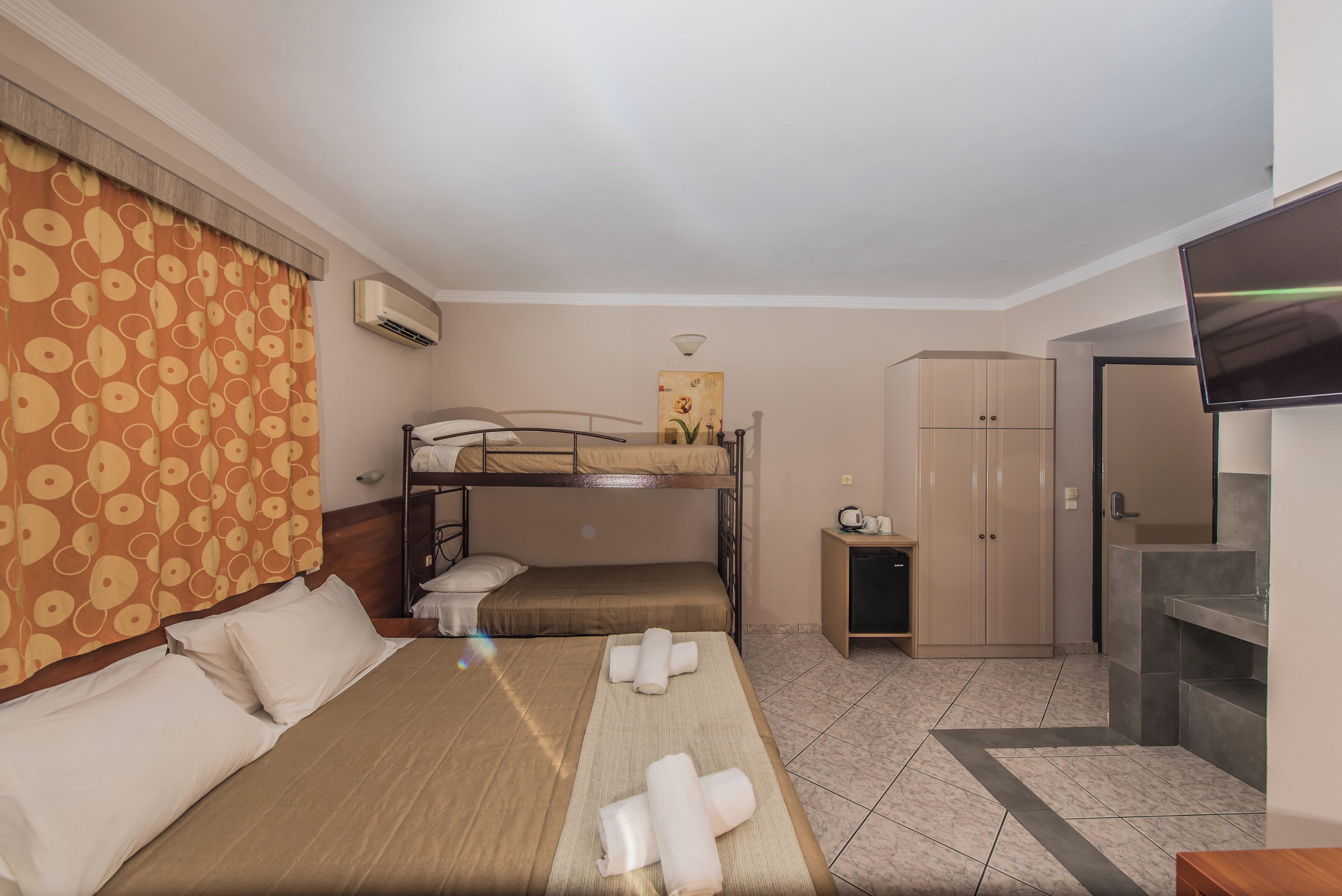 Una habitación de hotel con literas, un escritorio, un armario y un televisor.