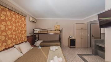 Una habitación de hotel con literas, un escritorio, un armario y un televisor.