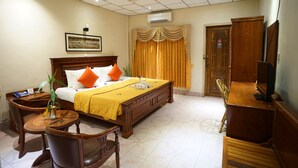 A hotel room with a bed, a desk, a chair, a television, and a wardrobe. - Royal Hotel (Battambang)