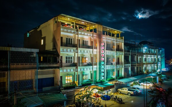 Un hotel de varios pisos con balcones y un letrero de neón que dice "ROYAL HOTEL".