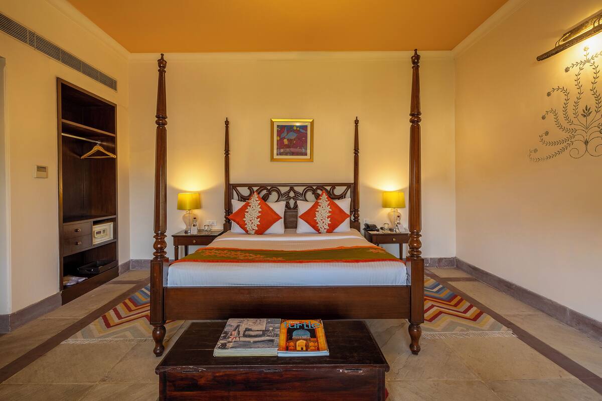 A four-poster bed with a wooden headboard, two bedside lamps, and a colorful bedspread.