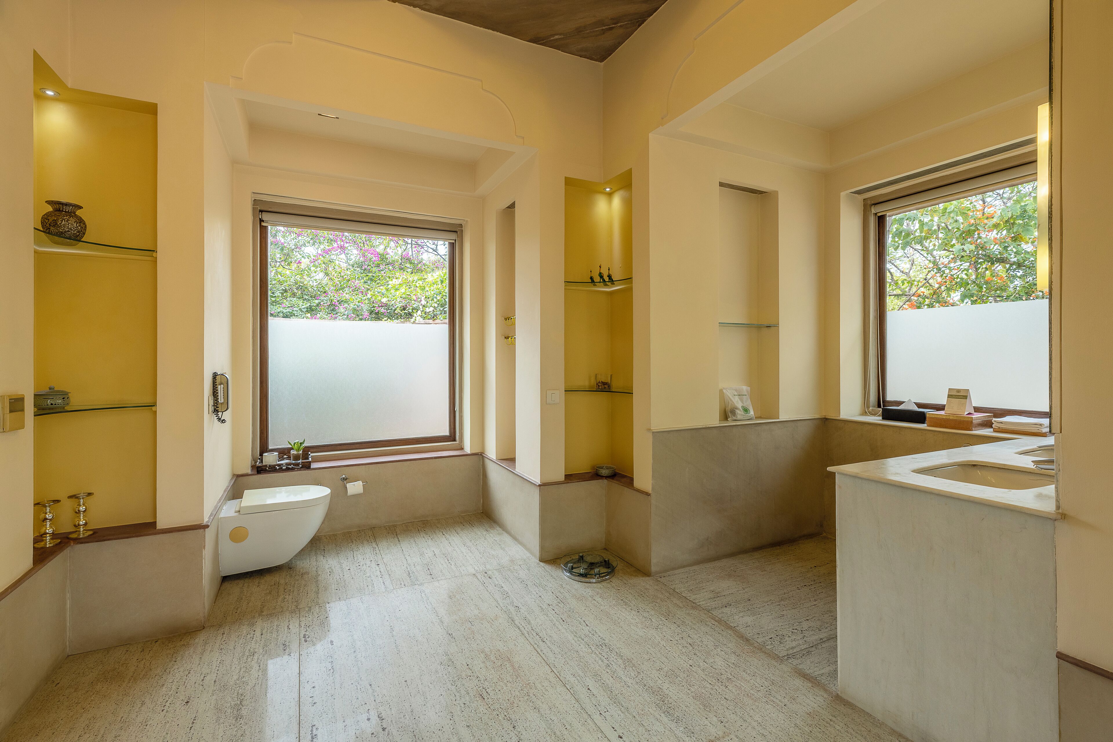 A modern bathroom with a freestanding bathtub, a large window, and built-in shelves.