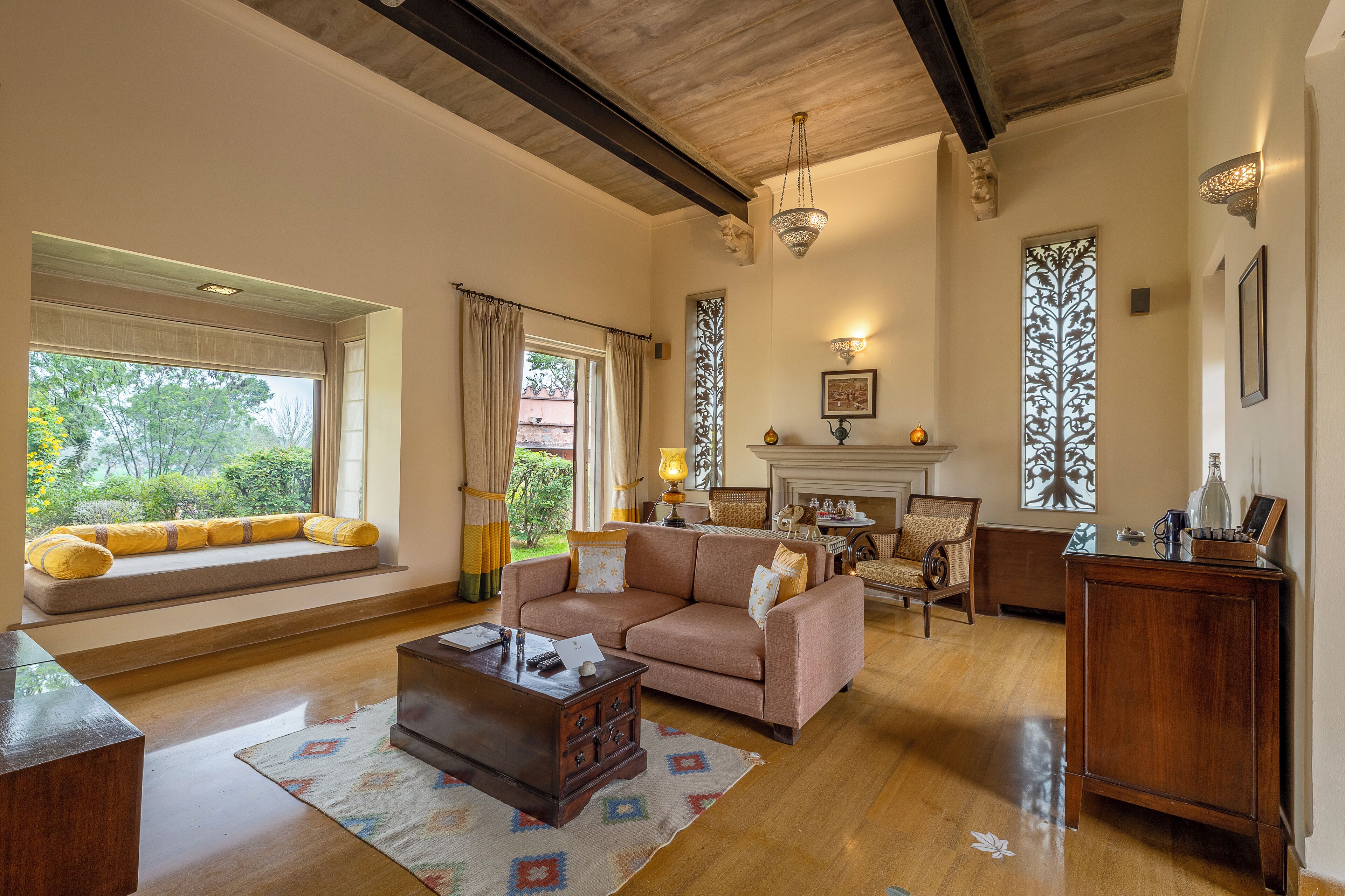 A spacious living room with a large window, a sofa set, a coffee table, and a fireplace.