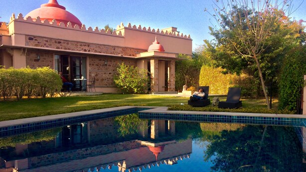 A pool with clear blue water, a building with a red dome, and a well-maintained garden. - The Tree of Life Resort & Spa, Jaipur (Amer)