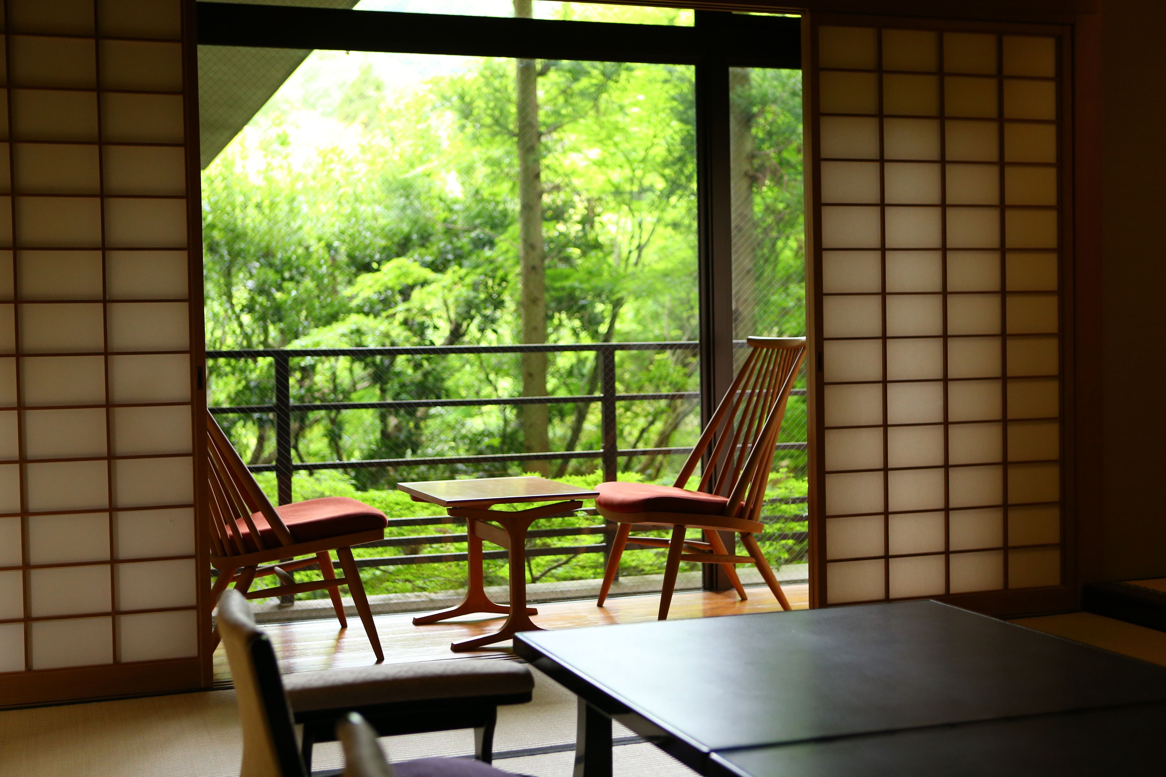 Una habitación con suelo de tatami, una mesa baja y dos sillas.