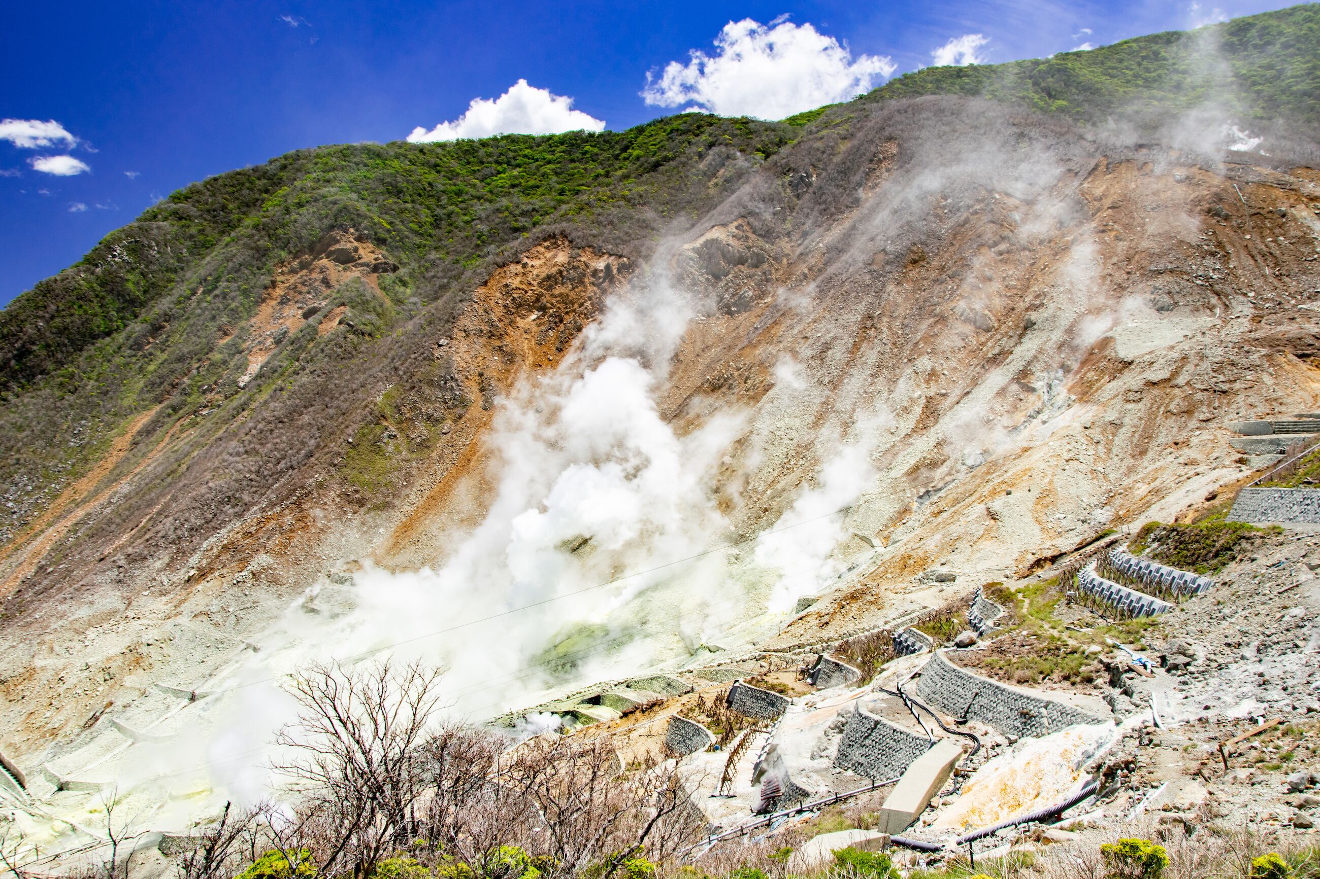 A geothermal area with steam vents and terraced structures.