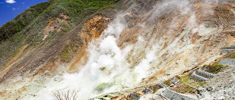 A geothermal area with steam vents and terraced structures.