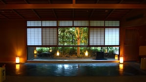A traditional Japanese room with tatami flooring, shoji screens, and a view of a bamboo garden.