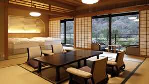 A traditional Japanese-style room with tatami flooring, a low table with chairs, and a bed with white bedding.