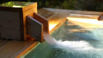 A wooden structure with a water feature, likely a hot tub, with a wooden box and a wooden slat.
