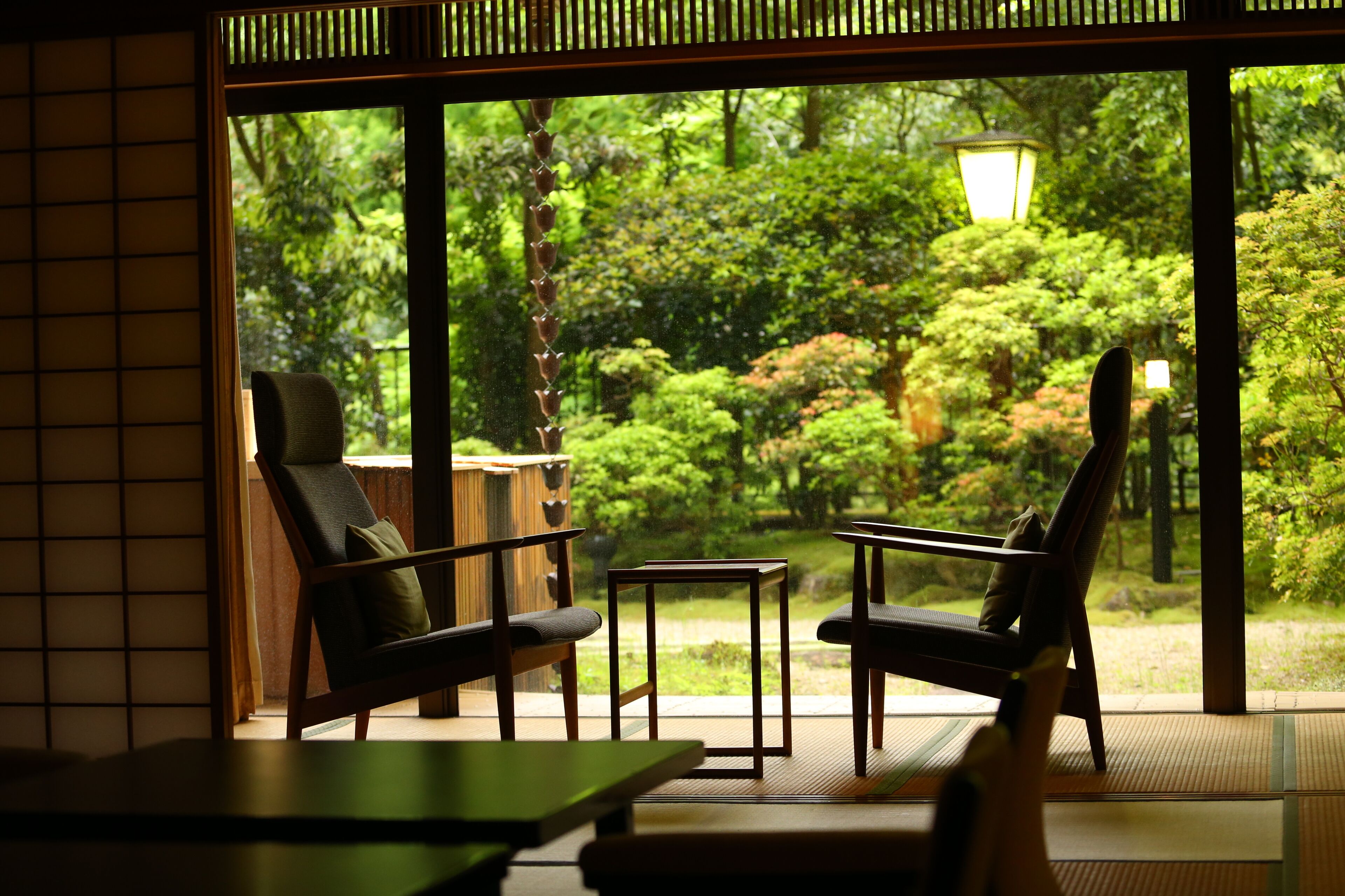 A traditional Japanese room with tatami flooring, a low table, and two chairs.