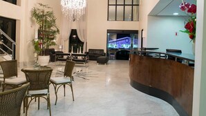 A spacious lobby with a reception desk, seating area, and a large chandelier.